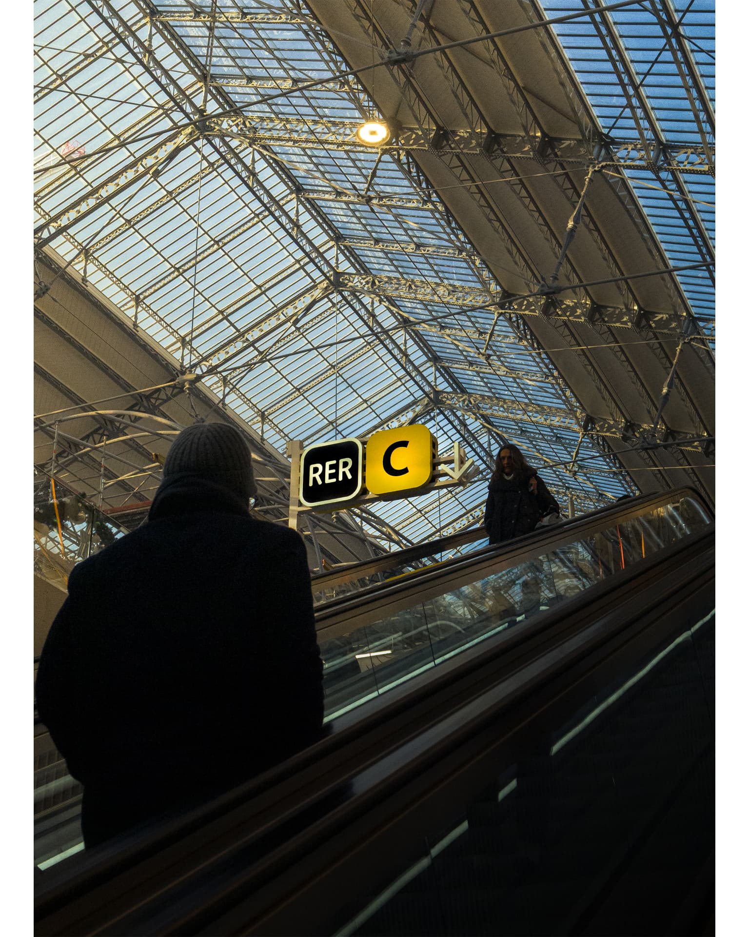 An RER C station escalator beneath a large metal-and-glass roof