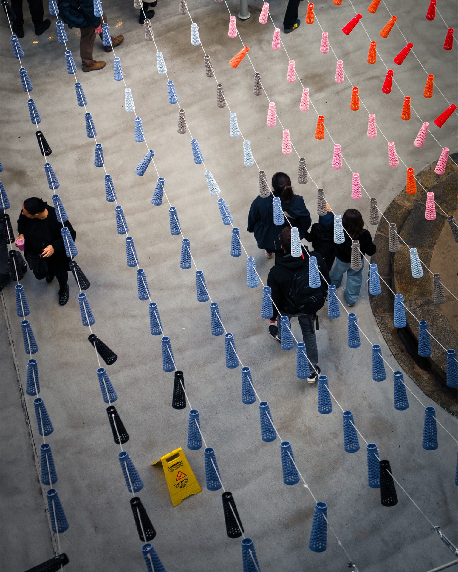 High-angle view of people walking among suspended colorful objects