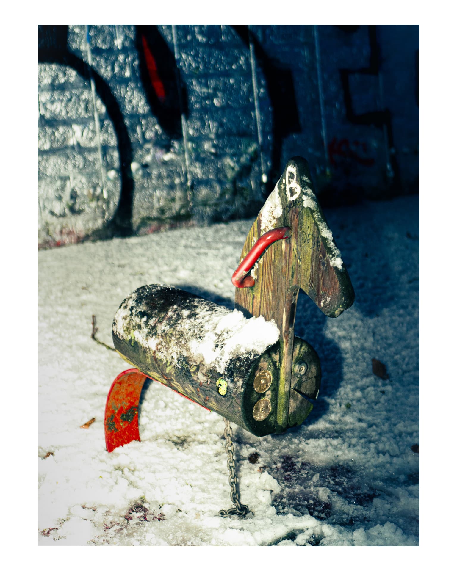 A small snow-covered rocking horse in cold blue light